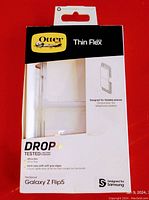 Front of box showing Otterbox Thin Flex branding, clear case visible inside, designed for Samsung Galaxy Z Flip 5