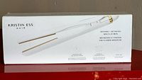 Box exterior showing Kristin Ess brand, image of flat iron, and product details including 'Defining + Detailing Mini Flat Iron' and '4 inch titanium plates with temperature sensing rapid heat technology'.