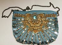 Front view of vintage evening bag showing blue fabric with gold sequin and bead embellishments plus central faux jewel and metal chain strap.