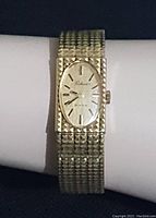Full view of vintage Birks ladies wristwatch with textured gold tone rectangular watch face and integrated band on white wrist display.
