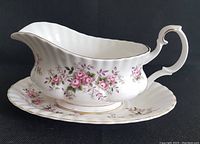 Side angle showing gravy boat on matching underplate with floral pattern and gold trim.
