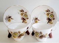 Two bone china tea cups and matching saucers displayed together showing floral pattern and shape.