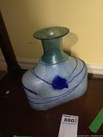 Overall view of the hand blown art glass vase highlighting its unique shape and blue swirl design.