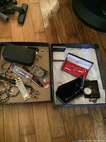 Two trays on wooden floor showing assorted jewellery and accessories