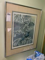 Framed print hung on wall with lot tag on corner.