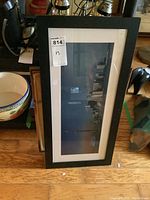 Wide shot of one framed print showing an abstract or photographic image in a black frame leaning on a surface.