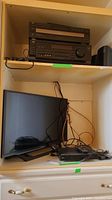Sony 32 inch television and LG Blu-Ray player displayed on shelves with cords and remotes.