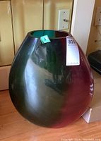 Front view of oval-shaped glass vase with green and purple tint showing reflections on surface