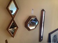 Four wall mirrors hanging on a wall, showing two vertical diamond-shaped mirrors, one octagonal mirror, and one long rectangular mirror.