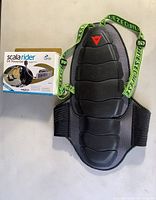 Dainese back protector with neon green straps and Scala Rider G9 Powerset bike intercom box on white surface