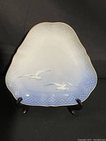 Single triangular Seagull plate on stand showing shape, pattern and gold trim