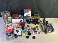 Overview of all cameras, lenses, tripods, lighting accessories, printer, film and memory cards on table