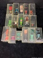 Top-down view of all 16 Matchbox Models of Yesteryear diecast model cars in their individual clear plastic display cases, showing different colors and styles