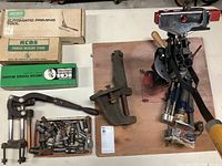 Photo showing variety of RCBS reloading equipment including stands, dies, and presses with some small parts.