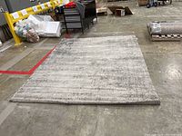 Full view of the large rectangular IKEA area rug lying flat on a concrete floor, showing size and general color.