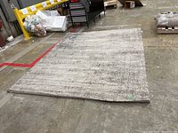 Full view of rectangular IKEA area rug laid flat on warehouse floor showing color and size.