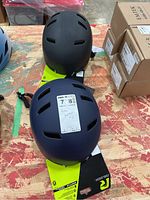 Two helmets displayed on table, one dark blue and one black, with Raleigh branding visible on packaging.
