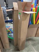 Two tall rectangular cardboard boxes containing corrugated paper rolls. One box has 'RED' handwritten on it. Boxes are open at the top showing flaps.