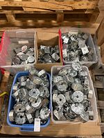 Five boxes filled with assorted metal electrical outlet boxes including gang boxes and round ceiling boxes, piled inside plastic and cardboard containers on a pallet.