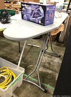 Side view of ironing board with boxed Hamilton Beach iron on top