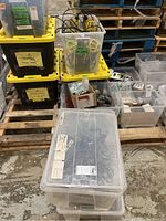 Five bins stacked and arranged on pallets, containing various light cages, cords and other electrical parts.