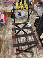 Two luggage racks shown standing and lying down; wooden rack with black straps displays scratches and wear, metal rack with yellow straps stacked behind.