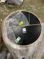 Two round wall mirrors stacked and partially wrapped in bubble wrap on a concrete floor. The mirrors have thin natural wood or bamboo style frames and measure approx. 31 x 31 inches.