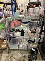 Full view of metal wire shelving unit with four shelves loaded with various household items for storage context illustration only. Shelving unit is empty in sale.