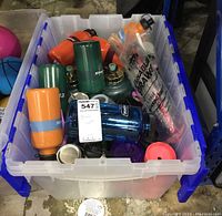 Full tote of assorted travel bottles and cups inside a clear plastic bin.