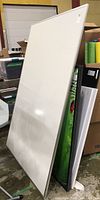Large whiteboard with metal frame, standing upright, showing full size and surrounding items for scale.