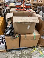 View of cardboard box labeled '24 ORANGE WORK LIGHTS' containing work lights and showing two double-head orange work lights on top.