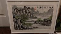 Full view of the framed Chinese hand-painted landscape with mountains, trees, water, a boat, calligraphy, and red seals.