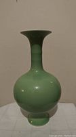 Front view of a green celadon vase showing bulbous body and narrow neck with flared rim