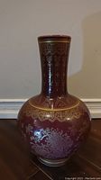 Front view of the red and gold Chinese vase showing full body and base decoration