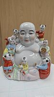 Front view of the hand painted porcelain Buddha figurine with seven children surrounding him, showing color details and facial expressions.