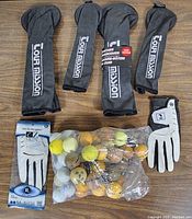 Photo showing 4 black leather Tour Mission golf head covers, 2 golf gloves (one white Dri Skin size ML, one black/white), and a bag of approximately 40 assorted golf balls in various colors and conditions.