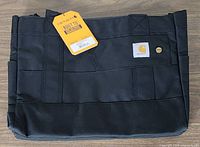Front view of black Carhartt horizontal zip tote with logo patch and tag