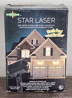 Photo of front of box showing Everstar Star Laser Projector branding and house decorated with star lights illustration.