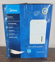 Box front showing Midea EasyDry dehumidifier features and specifications, including 22 pints/day capacity and energy star certification.