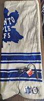 Photo showing Toronto Maple Leafs warming throw folded, displaying the logo and part of blue stripe design.