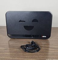 Virgin Mobile Call Me Valerie modem front view with power cable on wood surface.