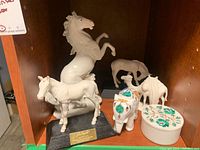 Overview photo showing four animal figurines including horses, camels, and the elephant figurine next to the floral trinket box.