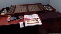 Front view of open wooden backgammon board on surface with accessories and book