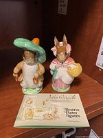 Front view of two ceramic Beswick Beatrix Potter figures with their original pamphlet.