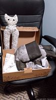 Manitobah Mukluks boots inside open box with fabric cat-shaped boot holder on chair