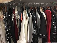 Clothing rack showing mix of sleeveless tops, blazers and sweaters on hangers