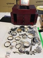 Open wood jewelry box with front panels and drawers ajar, jewelry arrayed