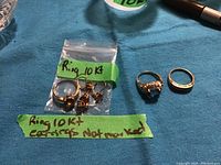 Two 10kt gold rings (plain band and citrine ring) alongside a bag containing two pairs of earrings