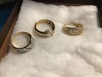 Three 14kt gold rings on white cushioned background