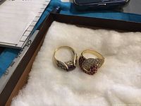 Two gold rings displayed on white fabric cushion inside box